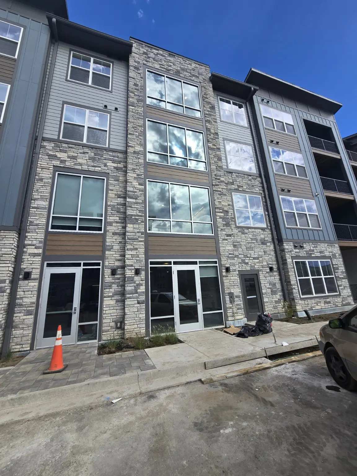 Multifamily elevation with tall aluminum window assemblies and glazed ground-floor entrances in Thornton