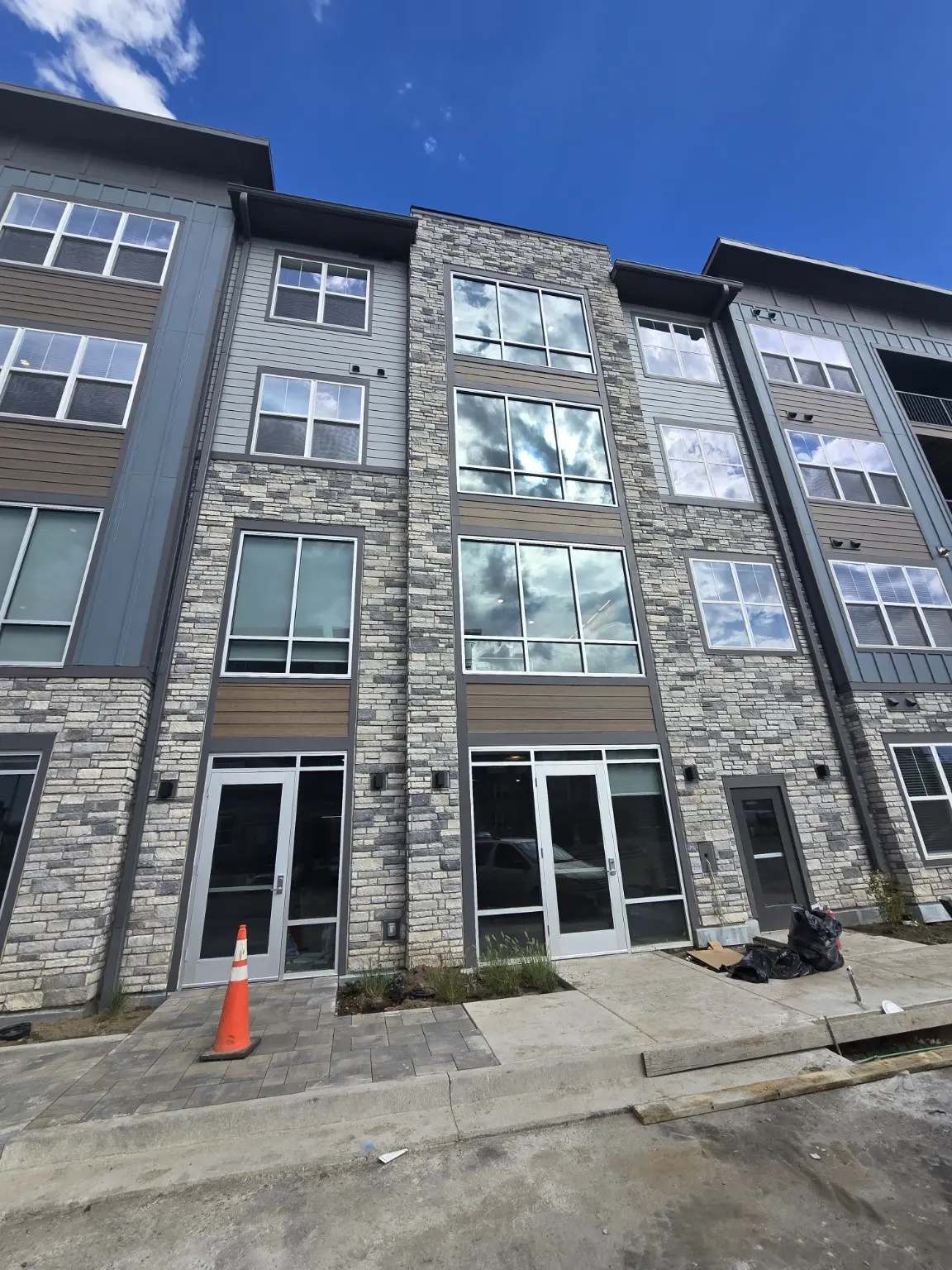 Completed aluminum glazing across a stone and siding facade with entrance doors in Thornton Colorado