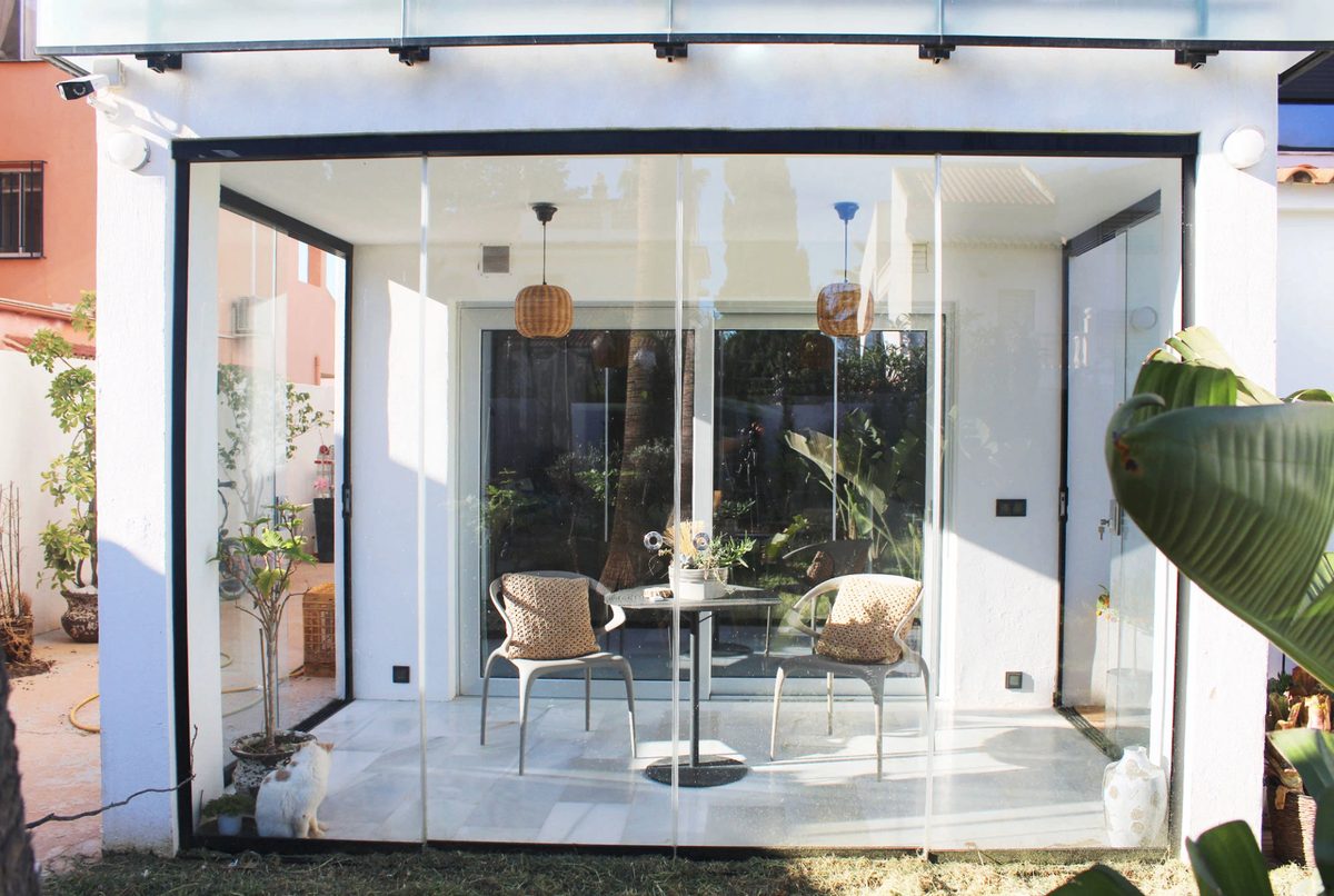 Open patio before and after a frameless glass enclosure — Before