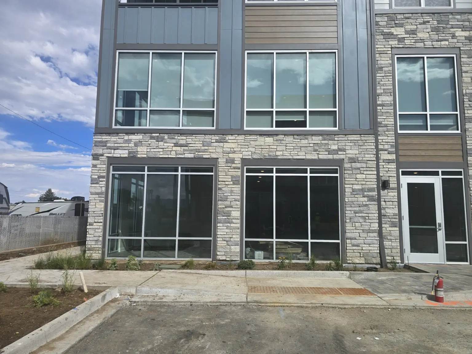 Stacked aluminum window assemblies above storefront openings and an aluminum entrance door in Thornton