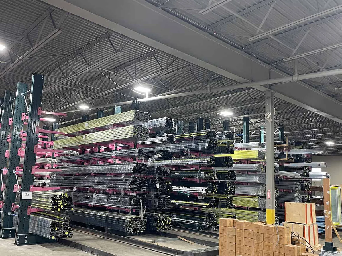 Stacked bundles of extruded aluminum profiles in a warehouse rack, cut ends facing the camera.