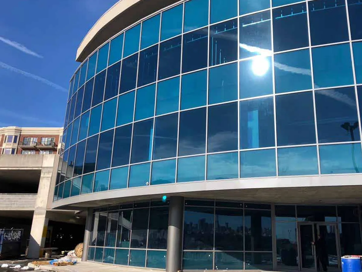 Curved multi-storey building clad in a continuous blue-tinted glazed curtain wall running unbroken across the floor lines.